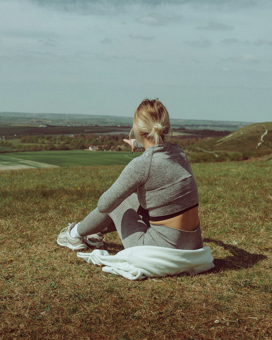 woman in purple long sleeve shirt sitting on brown grass field during daytime