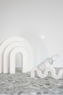 Minimalist white background with a close-up of a hyaluronic acid serum bottle and natural ingredients.