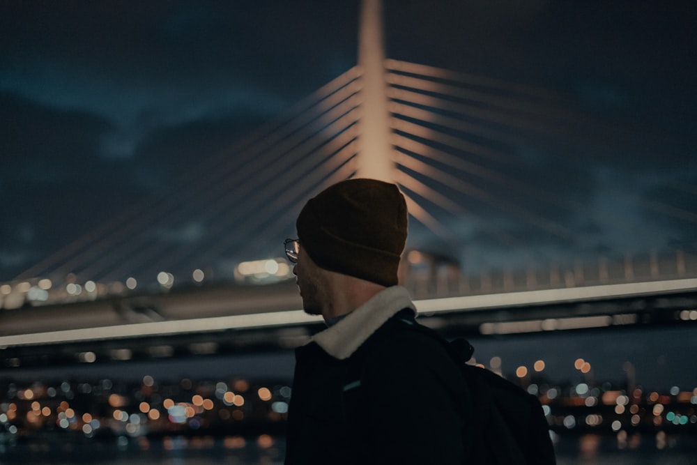 man in black jacket and black knit cap standing during night time