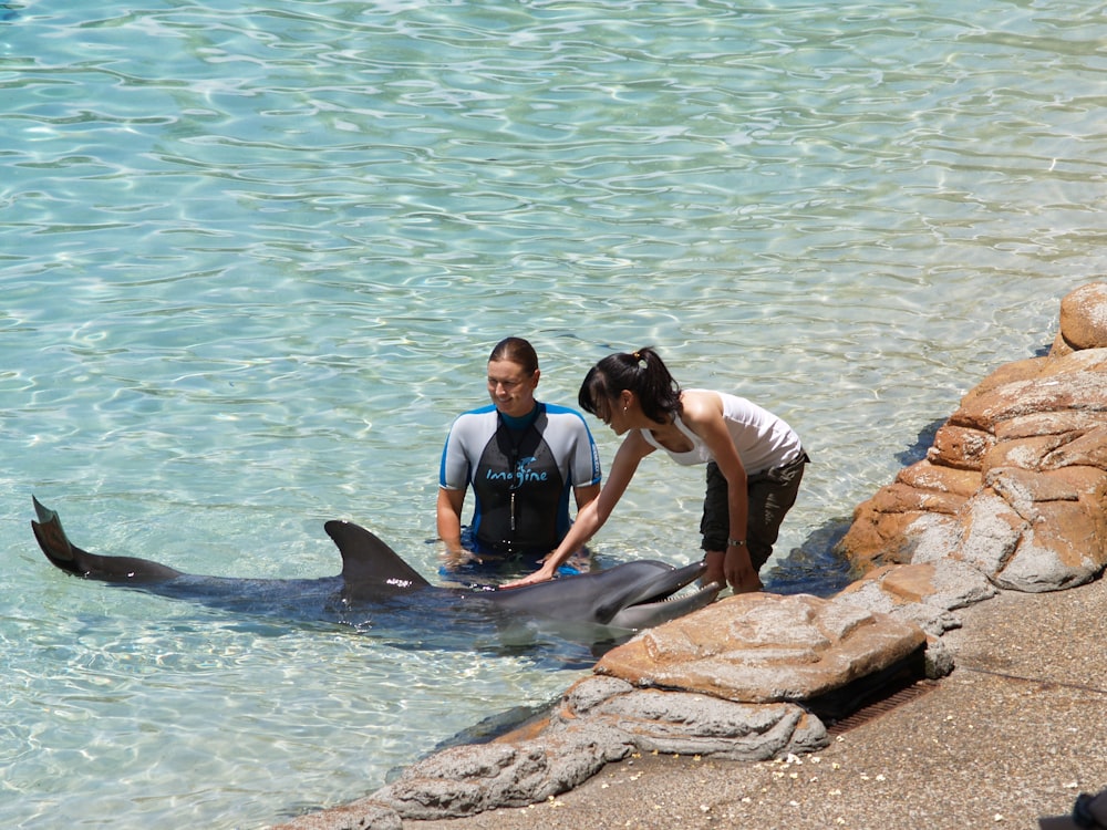 man and woman sitting on brown rock near body of water during daytime