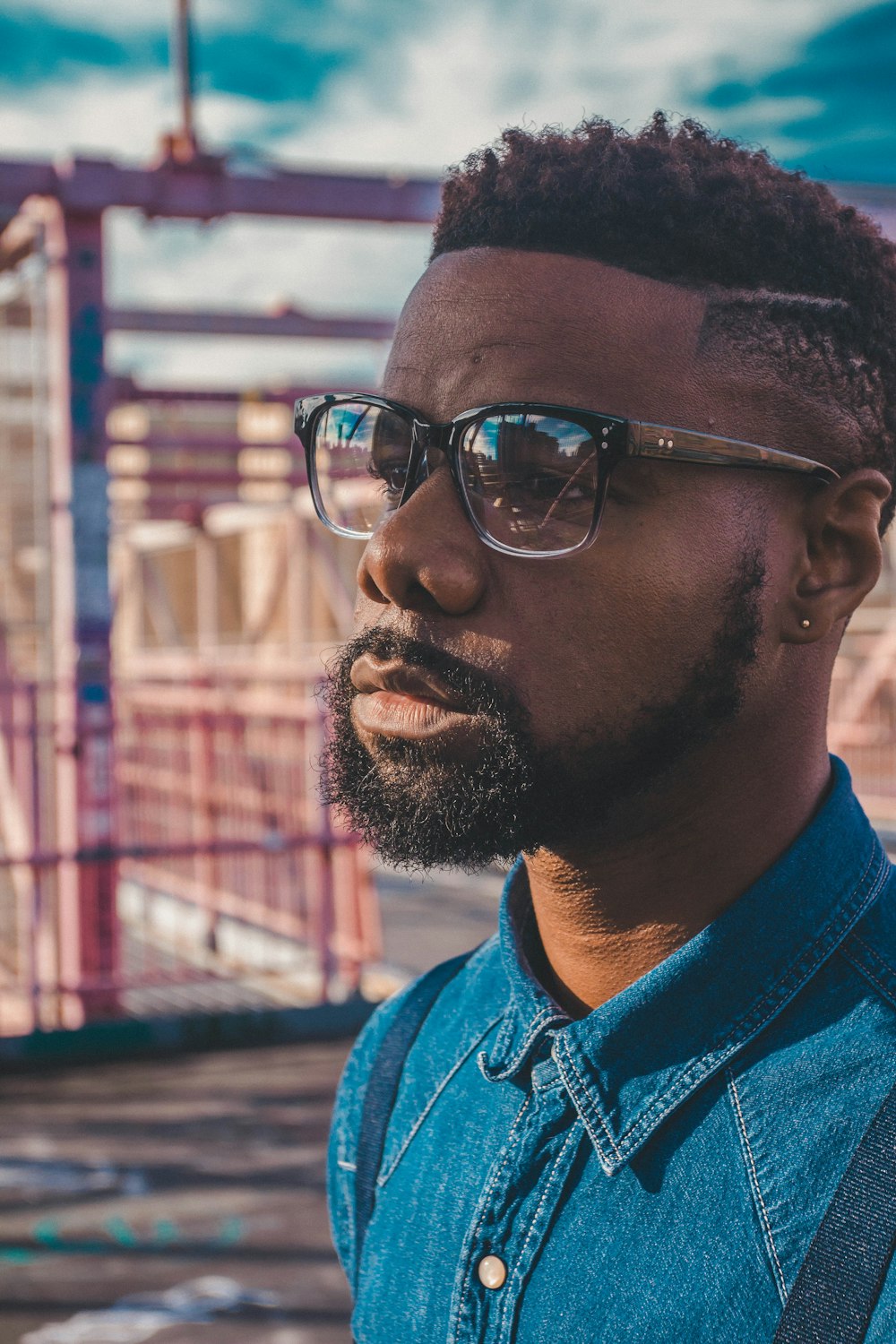 man in blue denim jacket wearing black framed eyeglasses