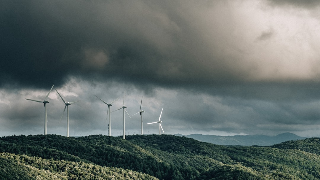 wind turbines on green mountain under gray cloudy sky