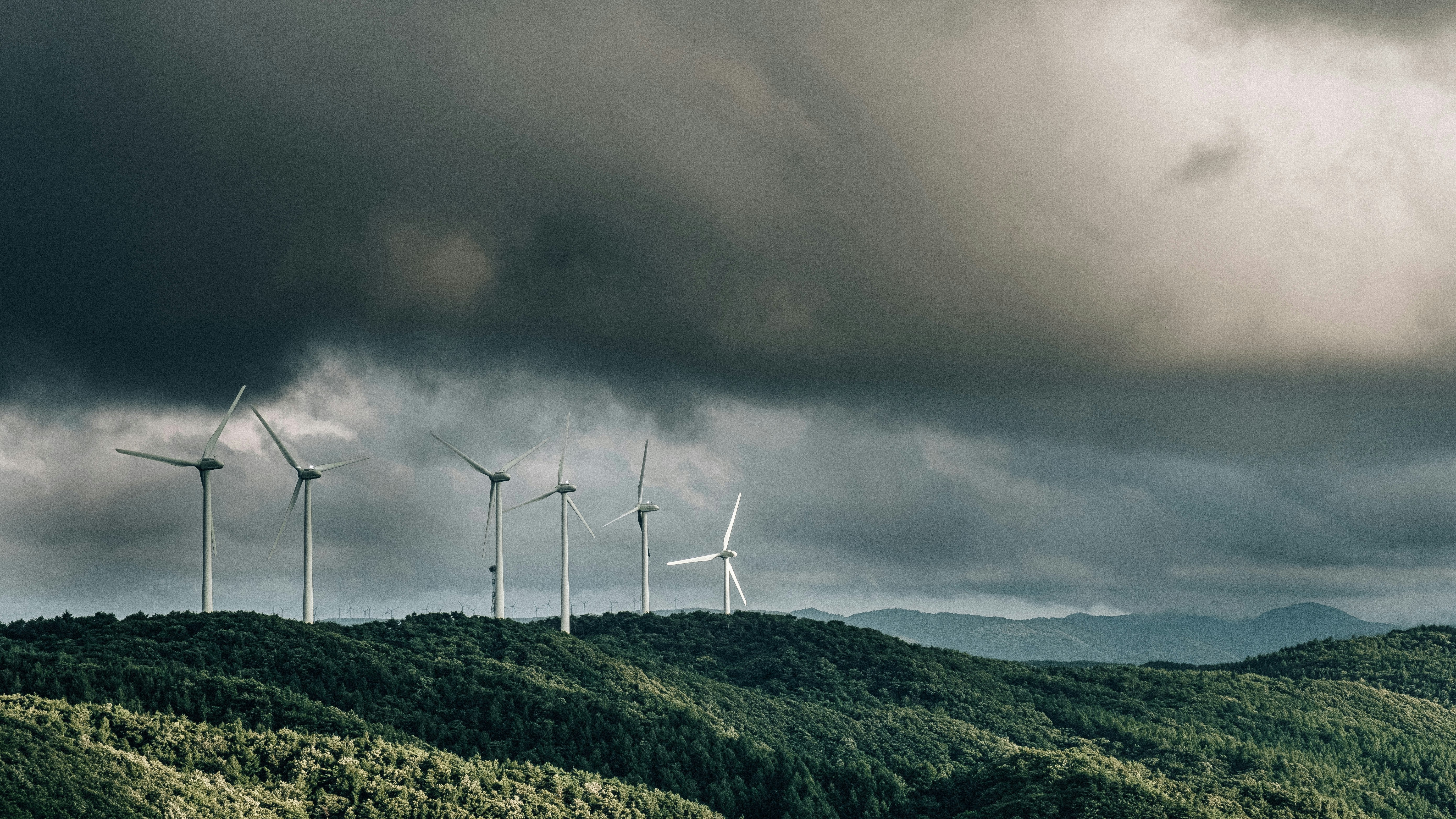 wind turbines on green mountain under gray cloudy sky