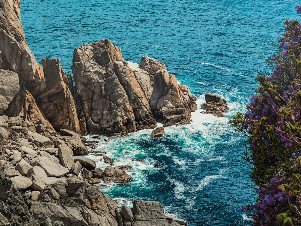 brown rocky mountain beside blue sea during daytime