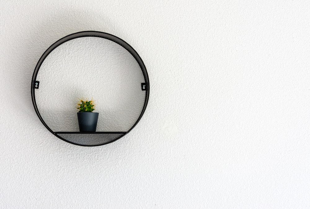 espejo redondo con marco negro sobre pared blanca