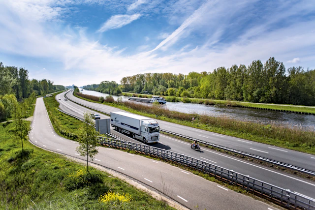 Witte vrachtwagen op een Nederlandse snelweg langs een kanaal; het soort wagenpark waarvan we de uitstoot berekenen.