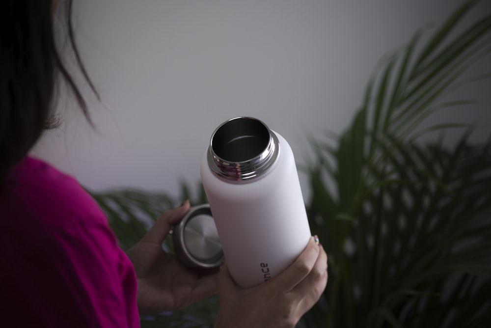 person holding white and black plastic bottle