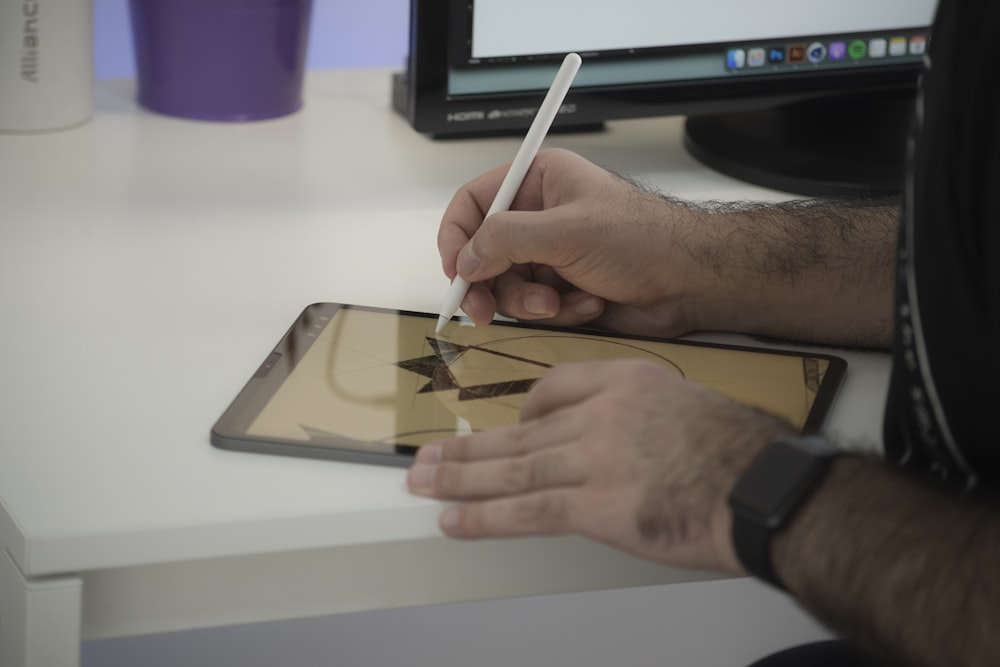 person holding white pen writing on white paper