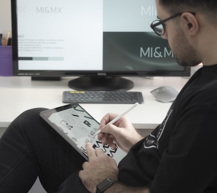 man in black long sleeve shirt sitting beside black flat screen computer monitor