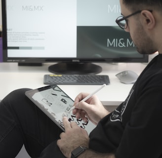 man in black long sleeve shirt sitting beside black flat screen computer monitor