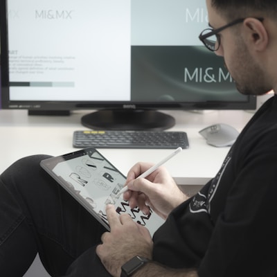 man in black long sleeve shirt sitting beside black flat screen computer monitor