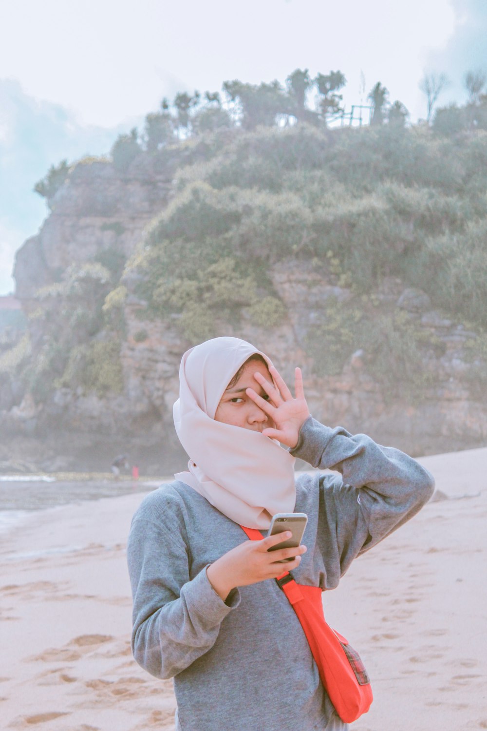 woman in gray hoodie covering her face with her hand