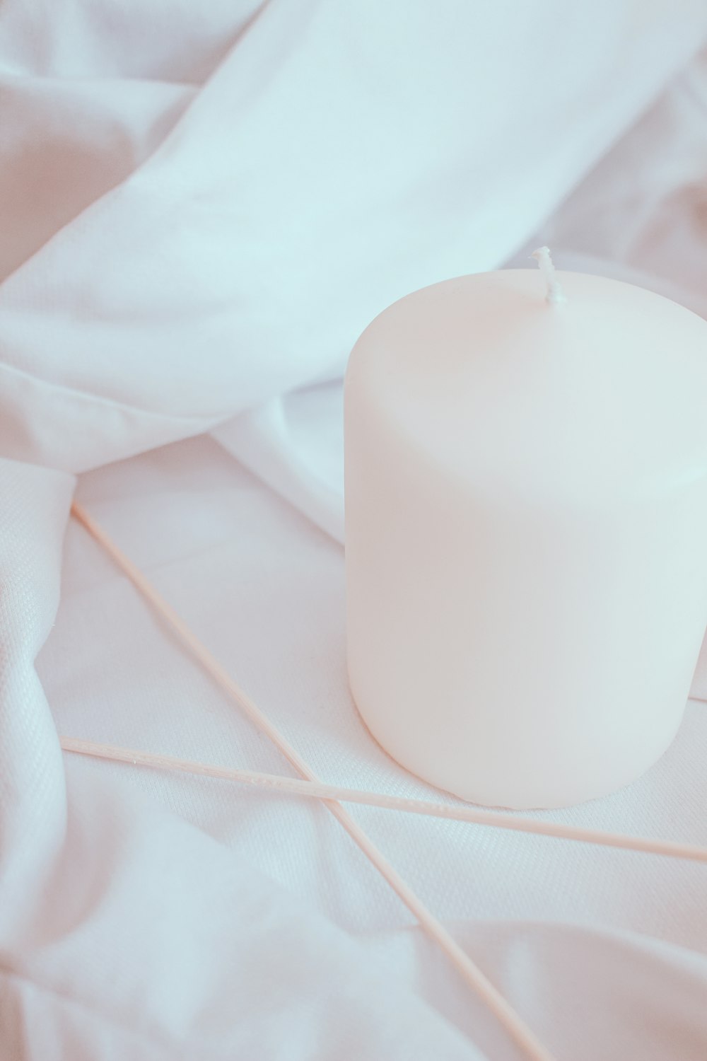 white pillar candle on white textile