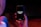 A hand is holding a black smartphone with the screen displaying the text 'OPPORTUNITY KNOCKS' in white font. The phone is surrounded by a dimly lit environment with hints of red and blue lighting.