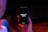 A hand is holding a black smartphone with the screen displaying the text 'OPPORTUNITY KNOCKS' in white font. The phone is surrounded by a dimly lit environment with hints of red and blue lighting.