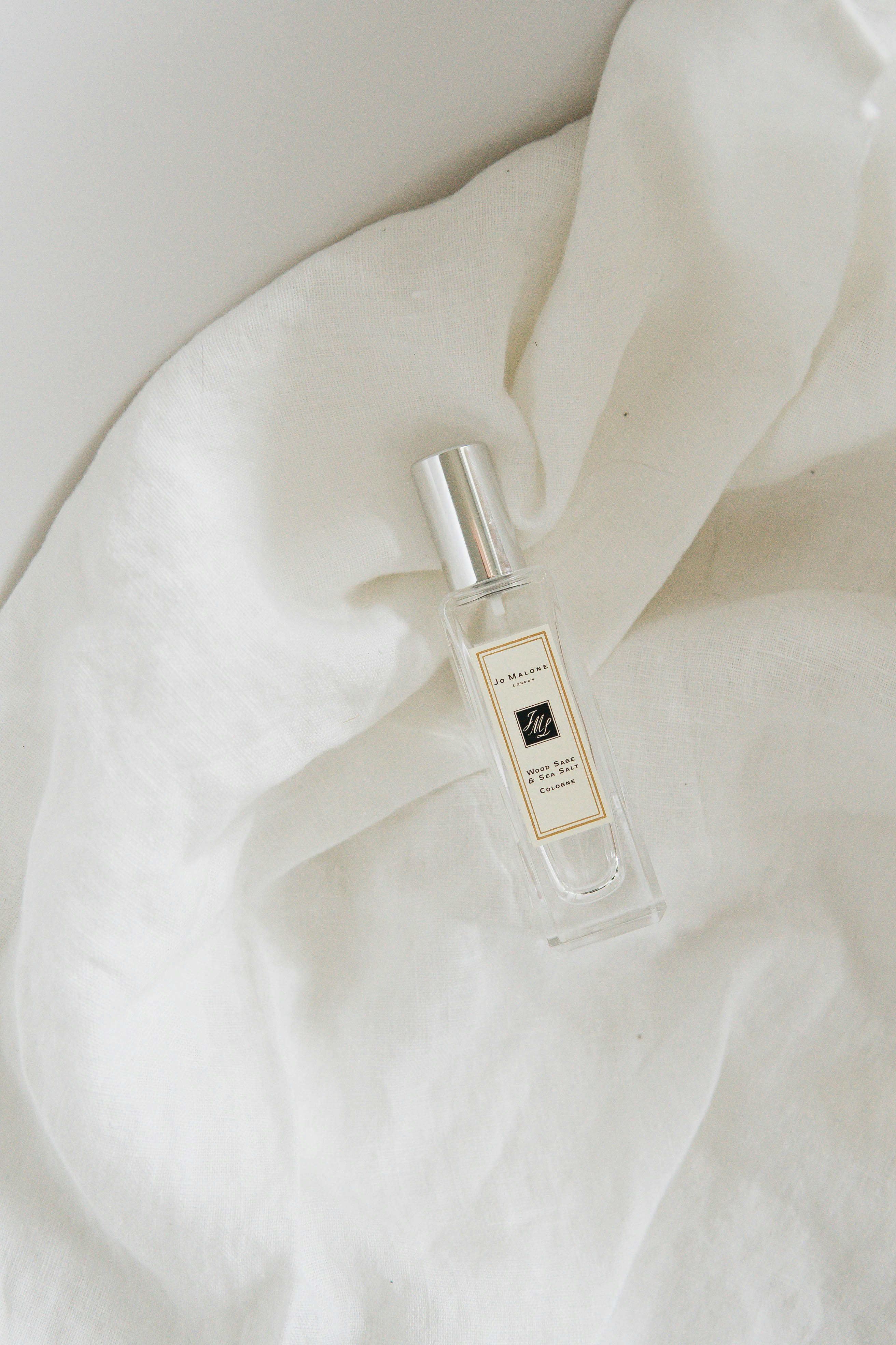 clear glass perfume bottle on white textile