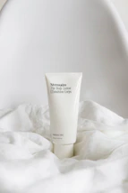 Elegant bottle of hand body lotion placed on a minimalist white surface with gentle lighting.