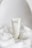 A sleek, minimalist tube of body lotion with black text is displayed elegantly on soft, white fabric, conveying a sense of purity and simplicity.