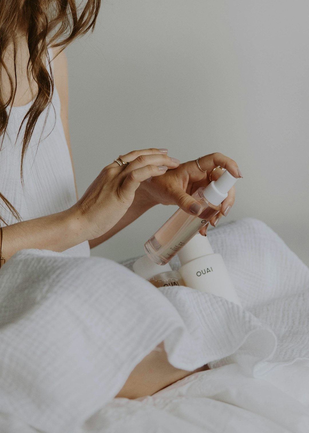 woman in white tank top holding white plastic bottle