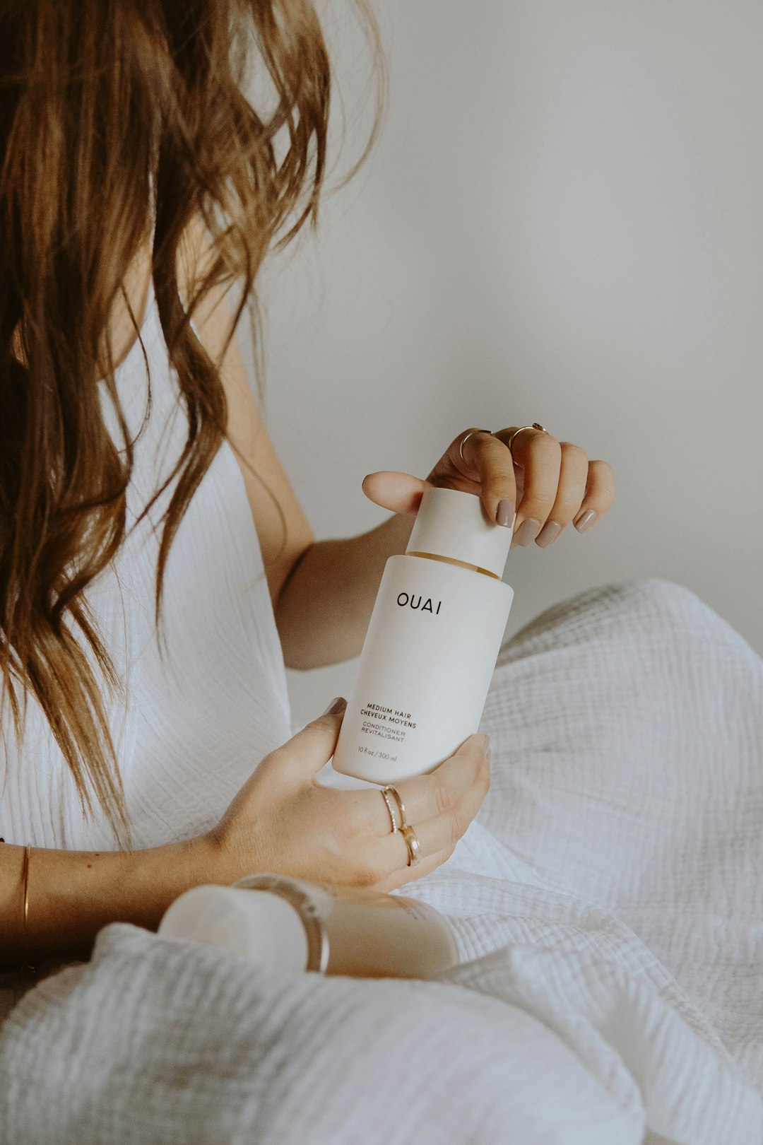 woman in white tank top holding white plastic bottle