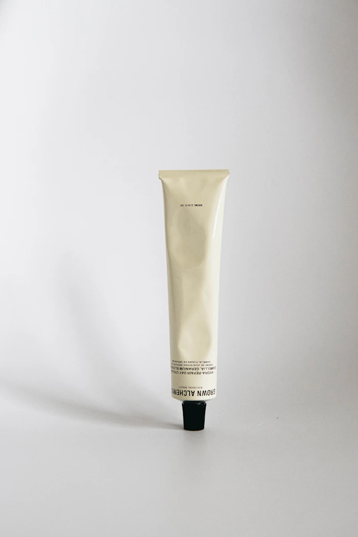 Cream body lotion tube standing on a white surface