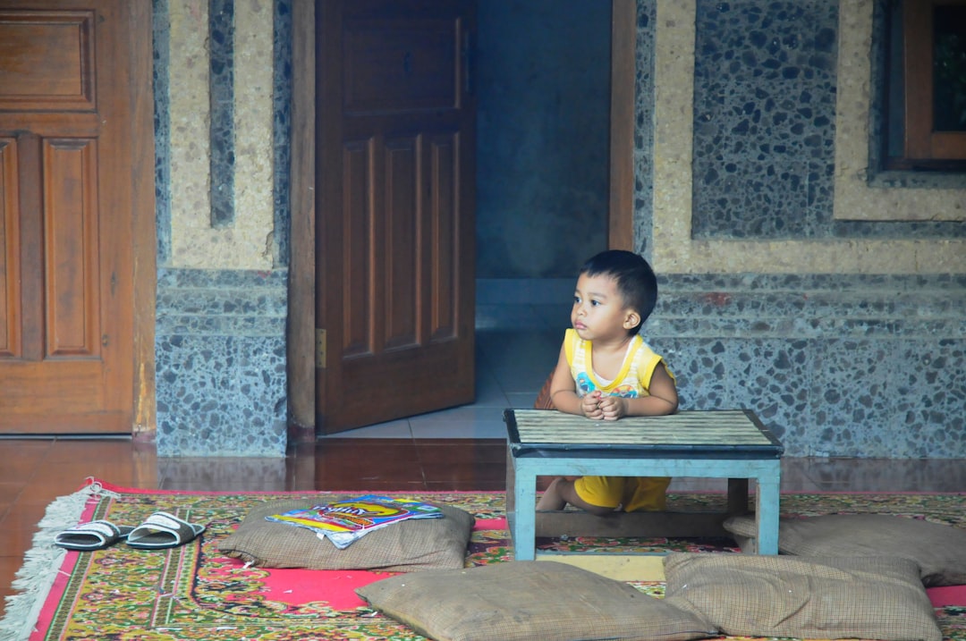 boy in yellow tank top sitting on brown wooden bench