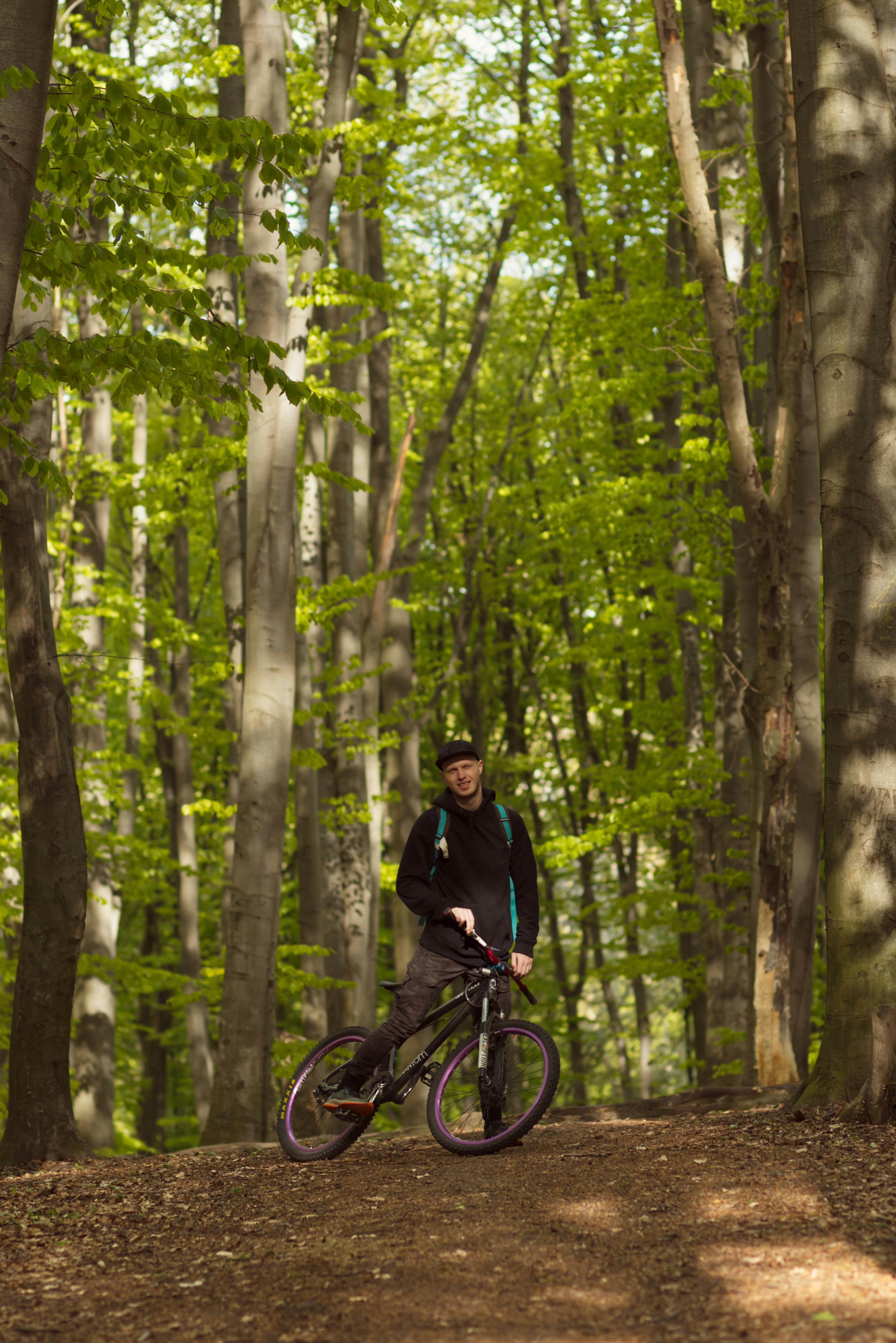 man in black jacket riding bicycle in forest during daytime