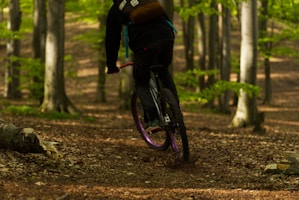 man in black jacket riding bicycle on forest during daytime
