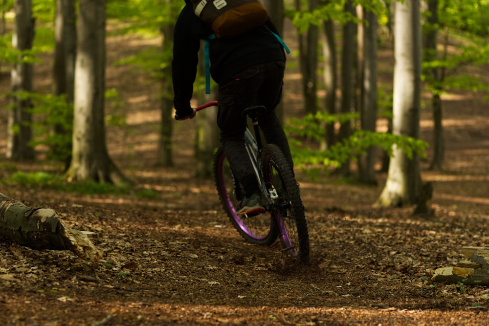 man in black jacket riding bicycle on forest during daytime