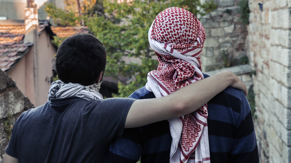 man in black shirt hugging woman in white and red hijab