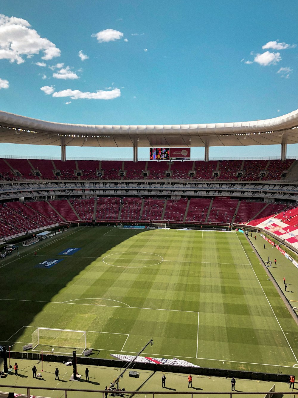 昼間の青空に映える緑と茶色のサッカースタジアム