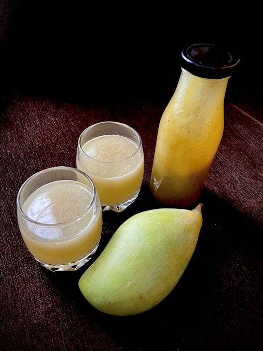 Close-up of a vibrant mango in a clear jar with fresh mango chunks inside