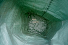 Inside a green textured bag, the words 'SELF ESTEEM' are arranged using wooden letter tiles. The perspective is from inside the bag looking toward the bottom.