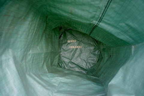 Inside a green textured bag, the words 'SELF ESTEEM' are arranged using wooden letter tiles. The perspective is from inside the bag looking toward the bottom.