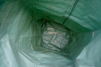 Inside a green textured bag, the words 'SELF ESTEEM' are arranged using wooden letter tiles. The perspective is from inside the bag looking toward the bottom.