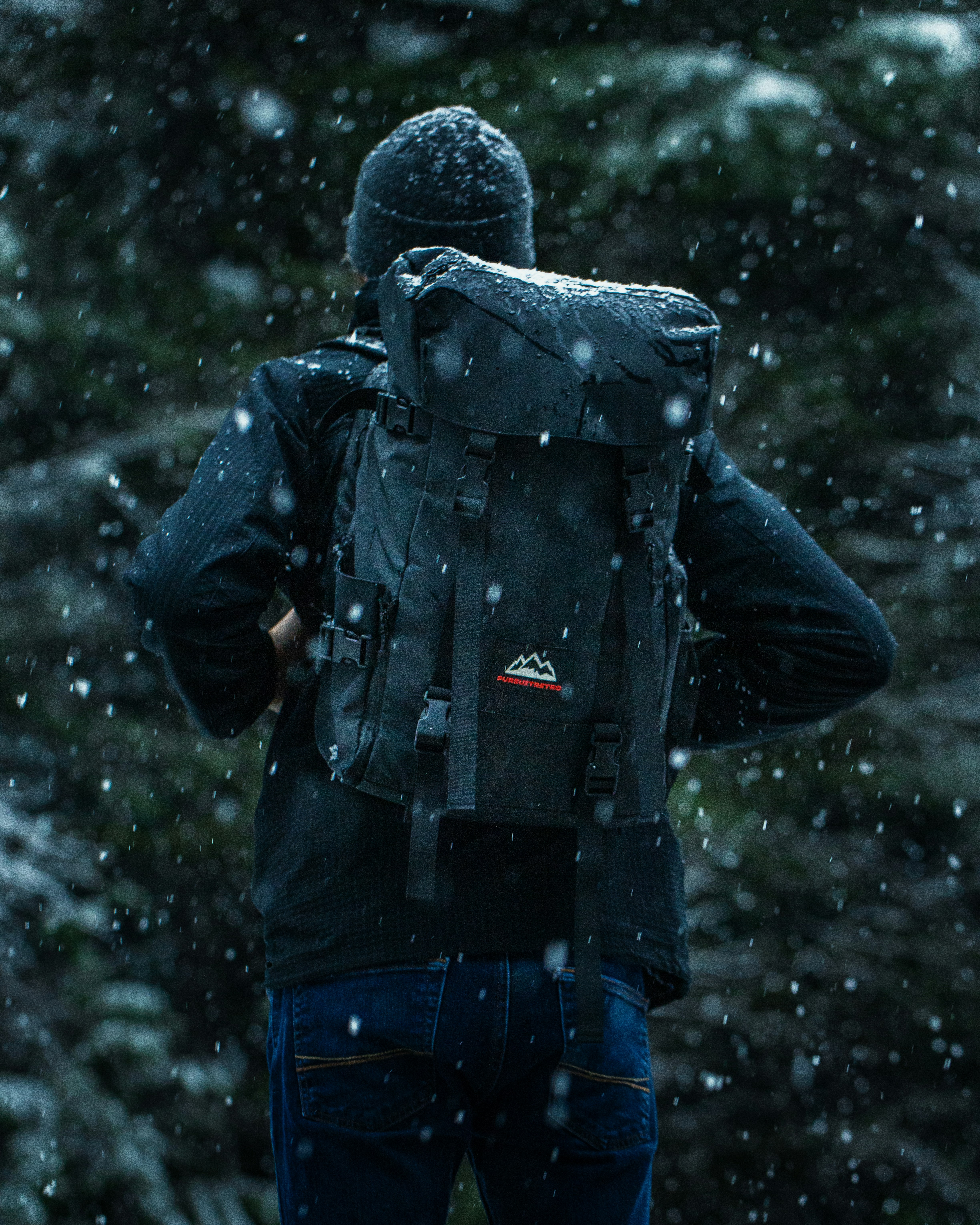 person in black jacket and blue denim jeans standing on snow covered ground