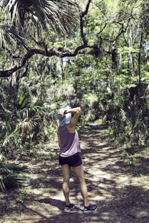 woman in pink tank top and black shorts standing on forest during daytime