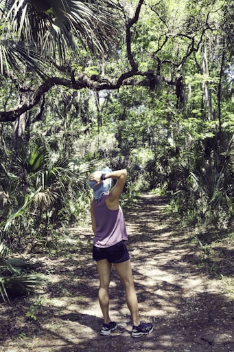 woman in pink tank top and black shorts standing on forest during daytime