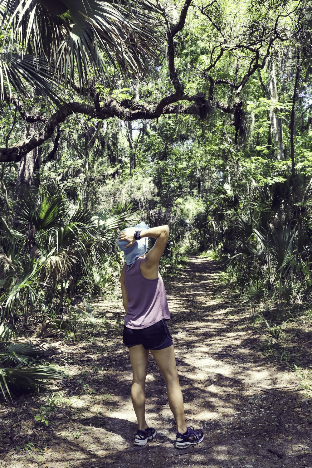 woman in pink tank top and black shorts standing on forest during daytime