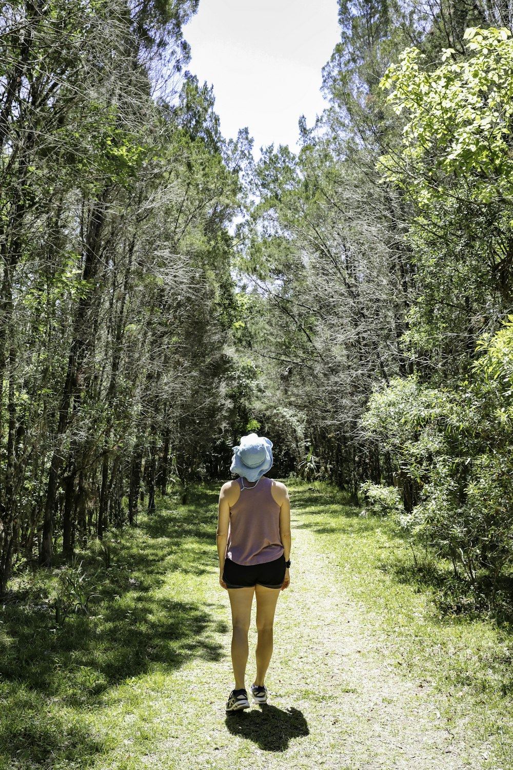 Femme en chemise bleue et jupe marron debout au milieu de la forêt pendant la journée