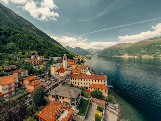 Brown and white concrete building near body of water under white clouds and blue sky during — Lake Como, Italy
