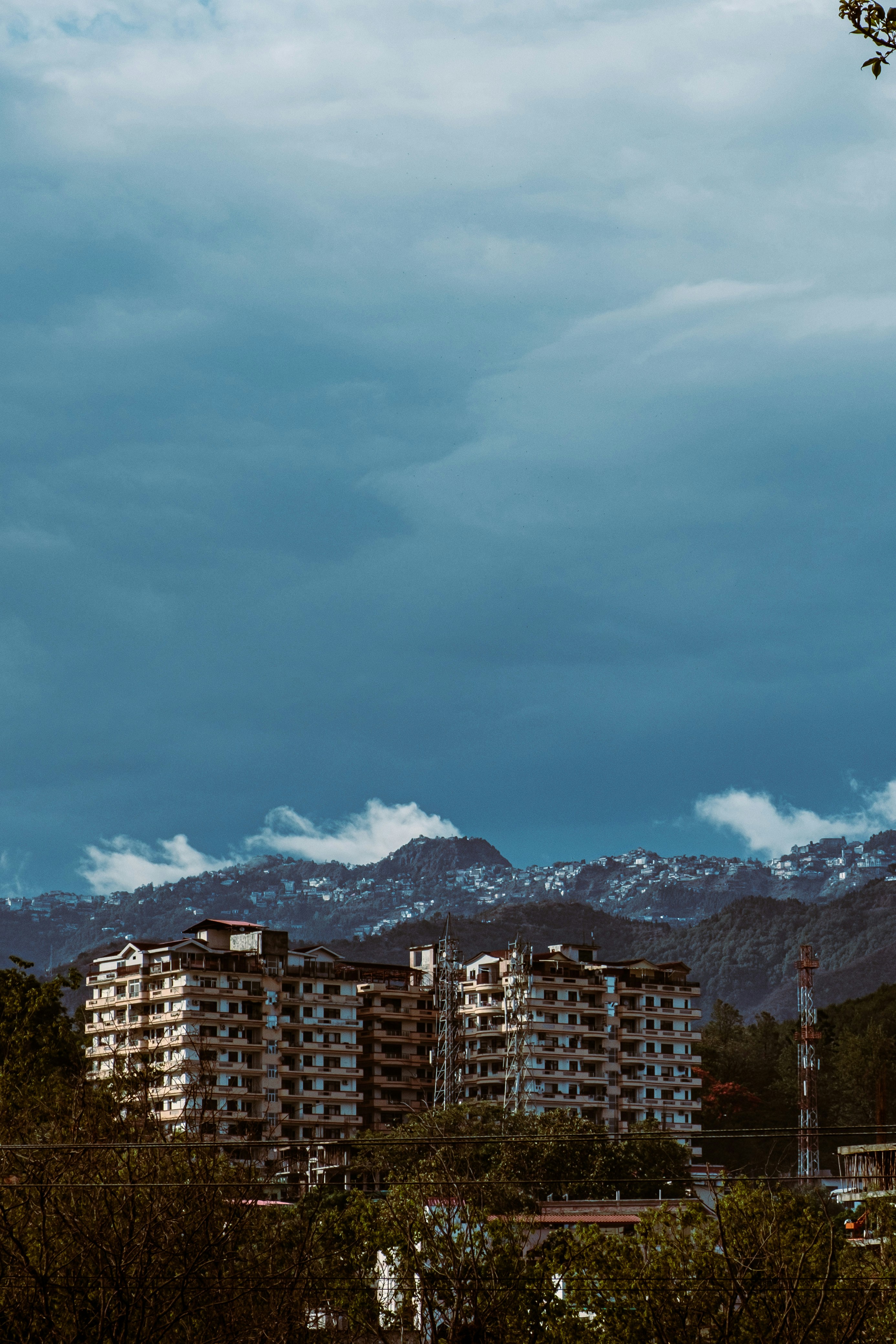 Bâtiment en béton brun près de la montagne sous les nuages blancs et le ciel bleu pendant la journée