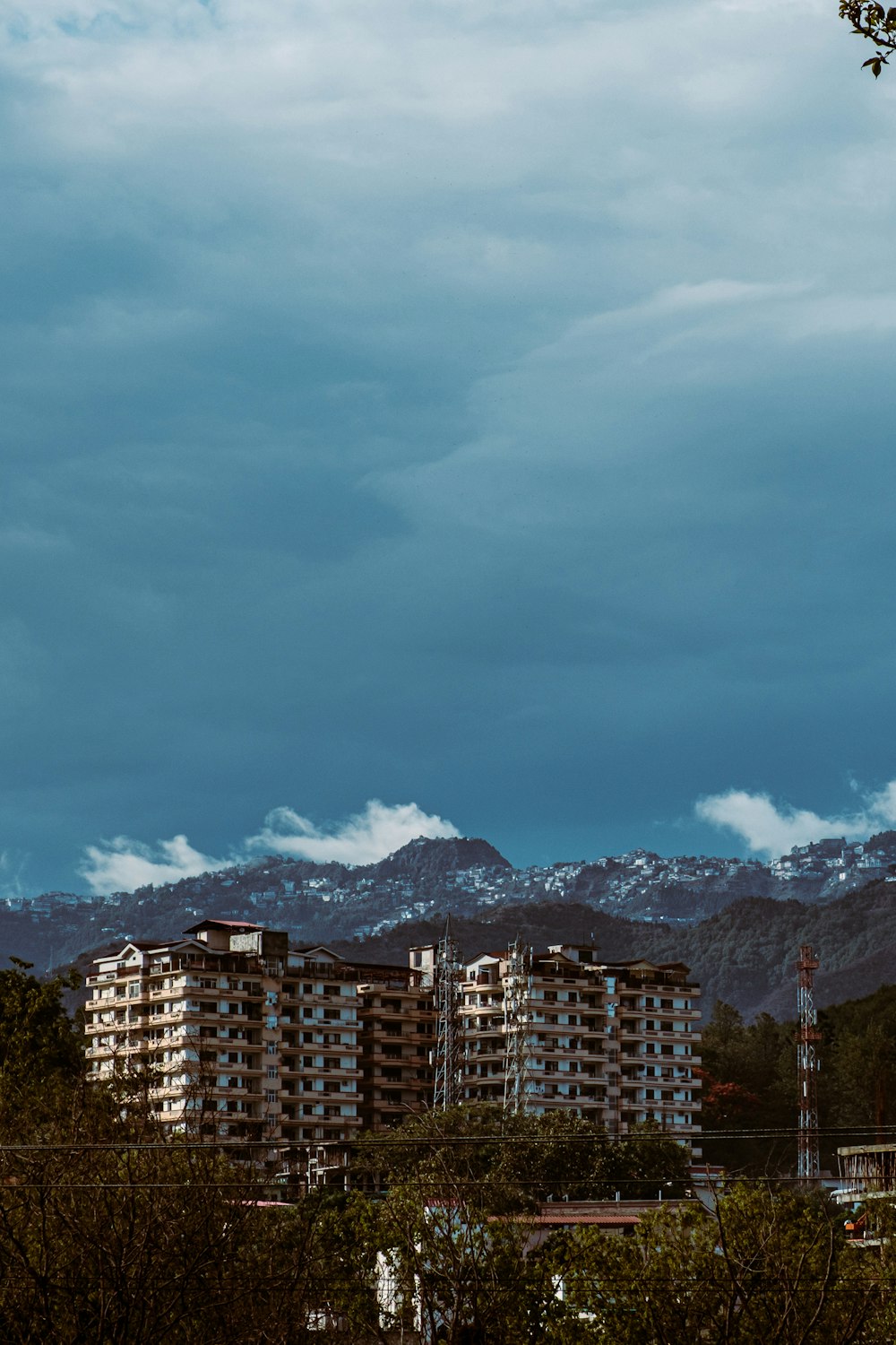 Braunes Betongebäude in Bergnähe unter weißen Wolken und blauem Himmel tagsüber