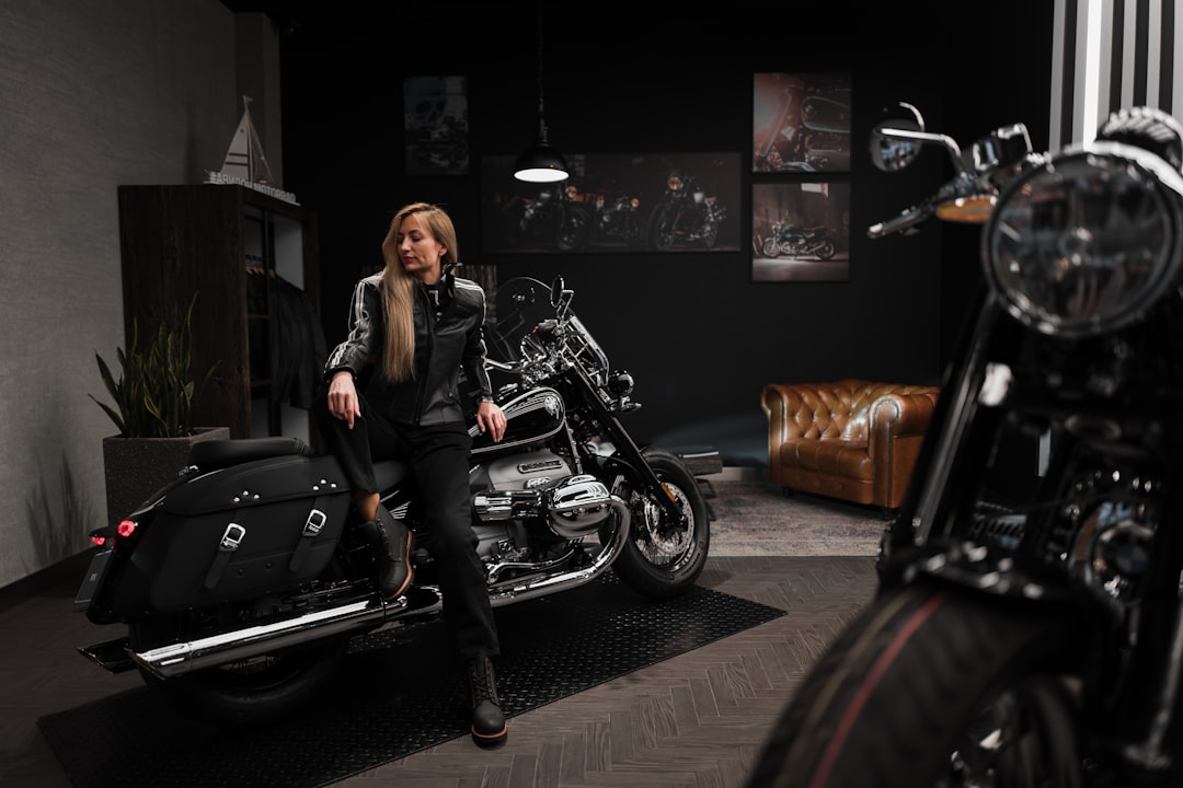 woman in black leather jacket and black pants sitting on black motorcycle