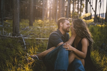 man and woman sitting on grass field during daytime