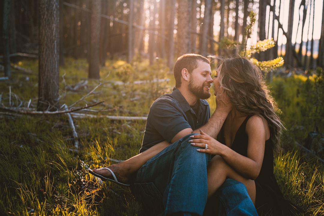 man and woman sitting on grass field during daytime