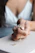 Close-up of a woman's hand wearing a delicate rose gold ring, softly lit against a neutral background.