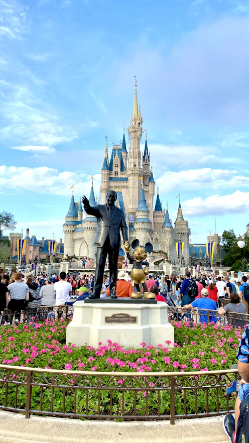statue of walt disney and mickey mouse in front of cinderella's castle in florida