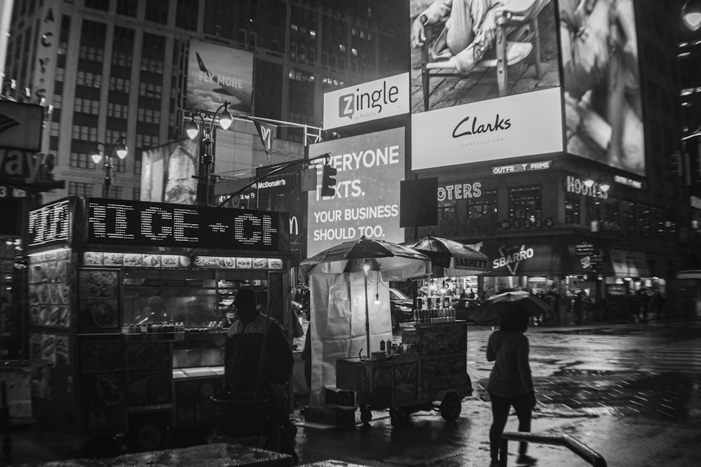 grayscale photo of people walking on street near store