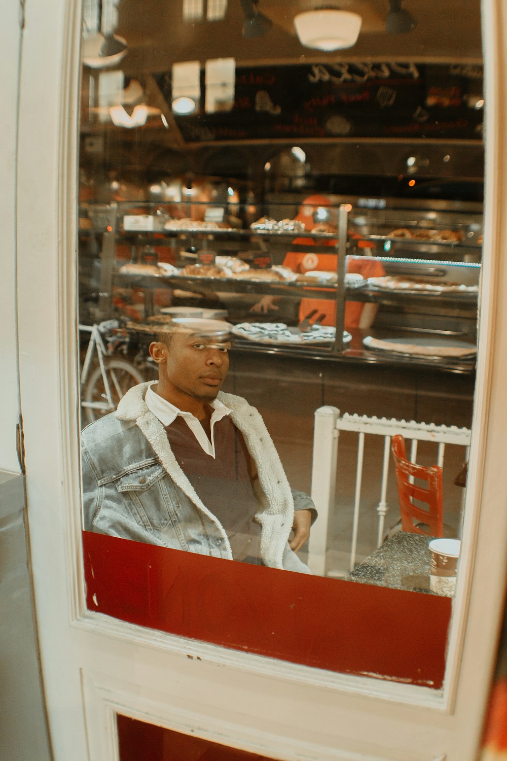 man in white dress shirt and white vest standing beside glass wall